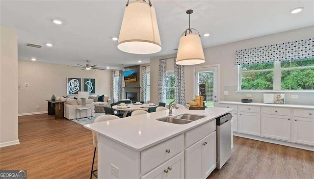 kitchen featuring wood finished floors, light countertops, a fireplace, white cabinetry, and stainless steel dishwasher