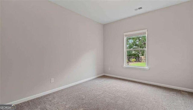 spare room with carpet floors, visible vents, and baseboards