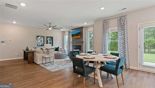 dining space with a fireplace, wood finished floors, visible vents, and recessed lighting