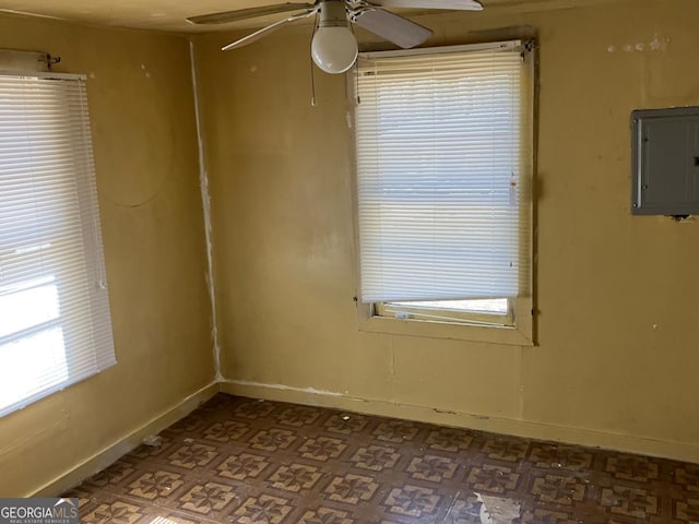 empty room with electric panel, baseboards, and a wealth of natural light