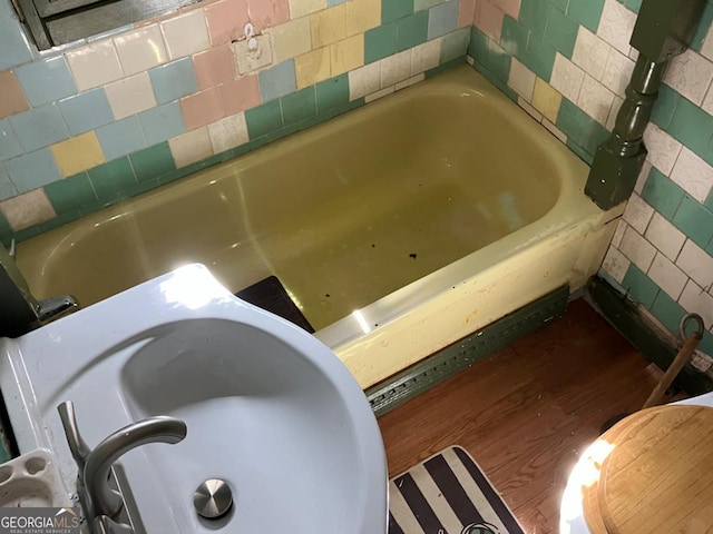 full bathroom featuring wood finished floors, a sink, and a tub