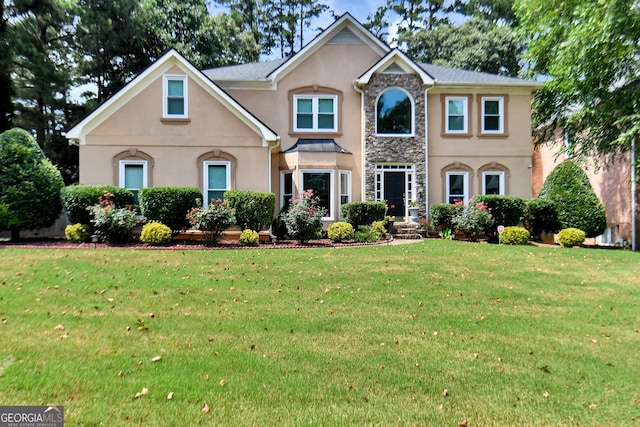 view of front facade with stone siding, a front yard, and stucco siding