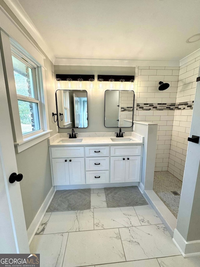 bathroom with marble finish floor, double vanity, walk in shower, and a sink