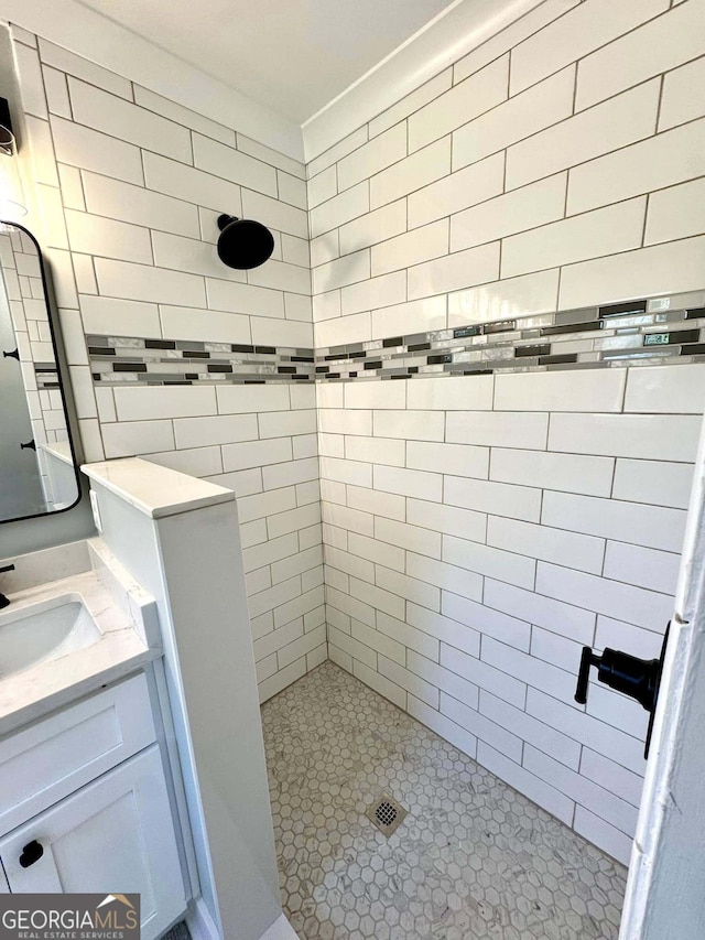 full bath featuring tiled shower and vanity