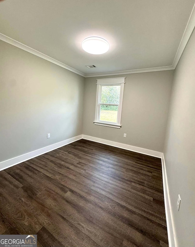 spare room featuring dark wood-style floors, visible vents, ornamental molding, and baseboards