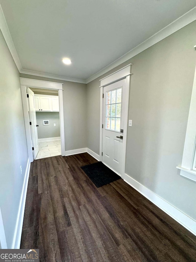 doorway featuring ornamental molding, baseboards, and wood finished floors