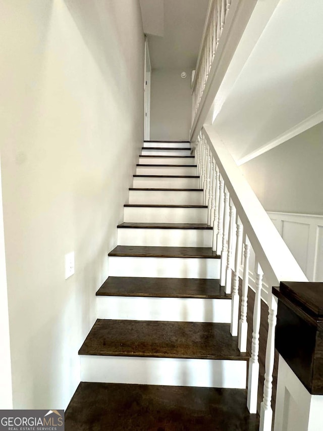 stairway featuring a wainscoted wall and a decorative wall