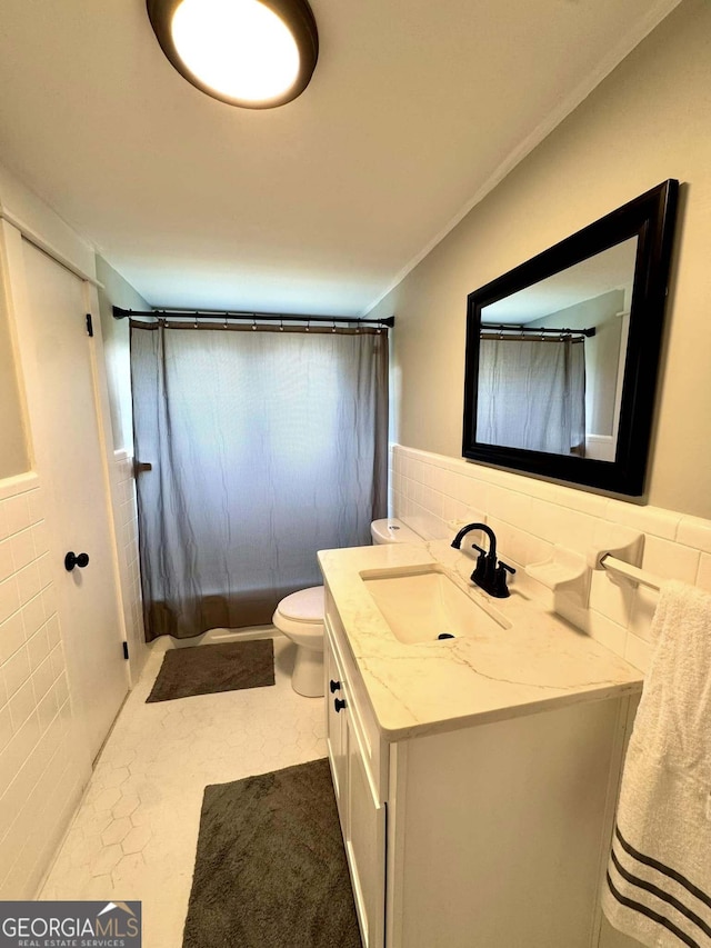 full bath with toilet, a shower with shower curtain, tile walls, and vanity