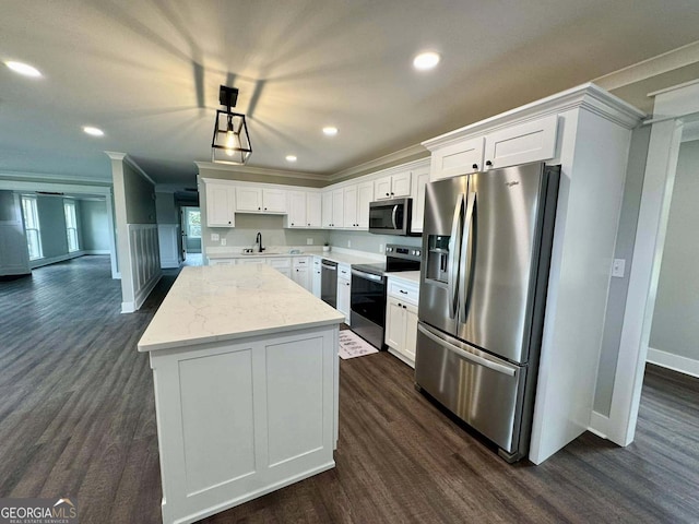 kitchen featuring dark wood-type flooring, a sink, ornamental molding, appliances with stainless steel finishes, and a center island