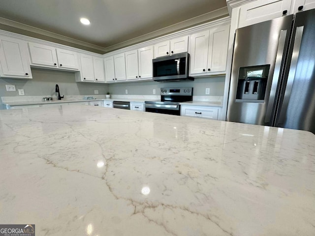 kitchen with stainless steel appliances, white cabinets, a sink, and light stone counters