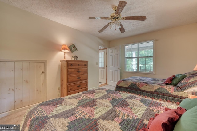 carpeted bedroom with a ceiling fan and a textured ceiling