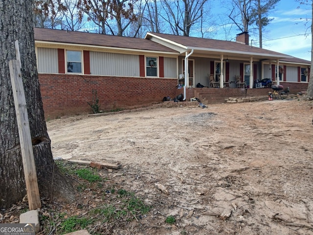 single story home with brick siding, a chimney, and a porch