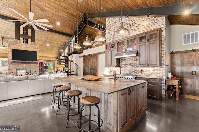 kitchen with visible vents, high vaulted ceiling, wood counters, a barn door, and wooden ceiling