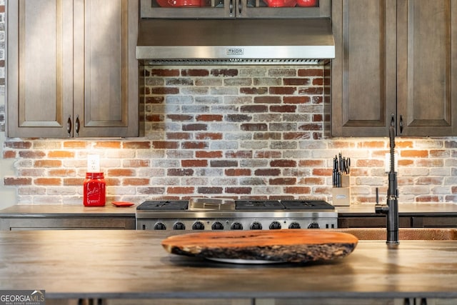 interior details featuring under cabinet range hood, wood counters, and range