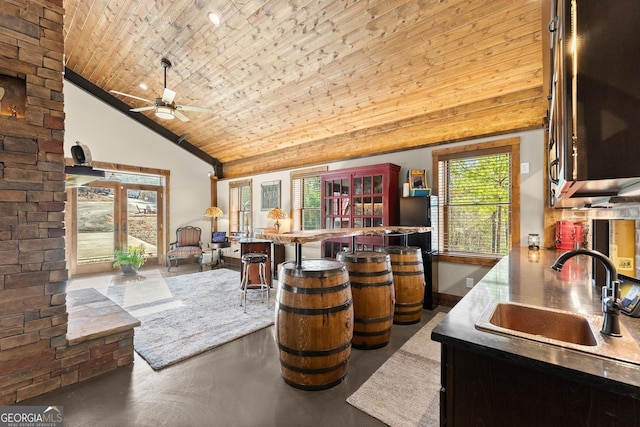 bar featuring a ceiling fan, a sink, stainless steel microwave, concrete floors, and wood ceiling