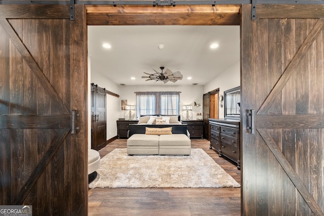 living area featuring a ceiling fan, a barn door, recessed lighting, and wood finished floors