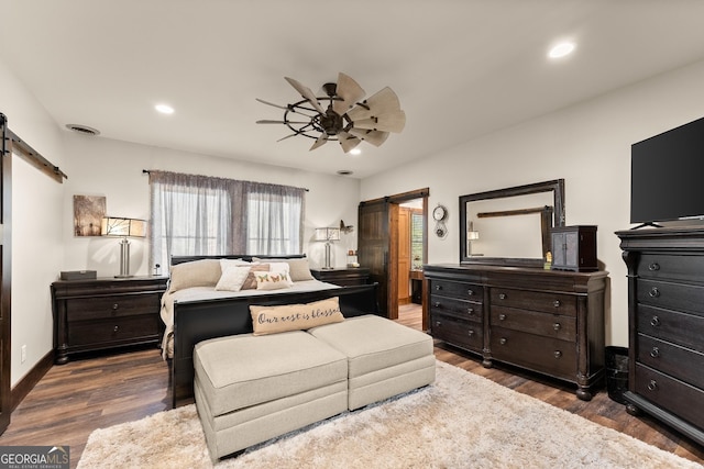 bedroom featuring visible vents, recessed lighting, a barn door, and wood finished floors