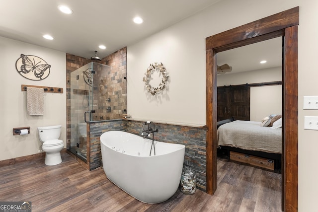 ensuite bathroom with wood finished floors, recessed lighting, a stall shower, a freestanding bath, and toilet