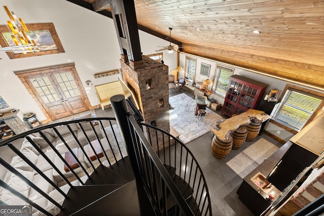 staircase with a ceiling fan, concrete floors, high vaulted ceiling, a fireplace, and wooden ceiling