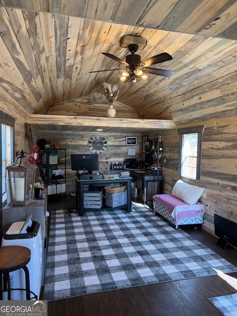 living area with a ceiling fan, vaulted ceiling, wooden ceiling, and wood walls