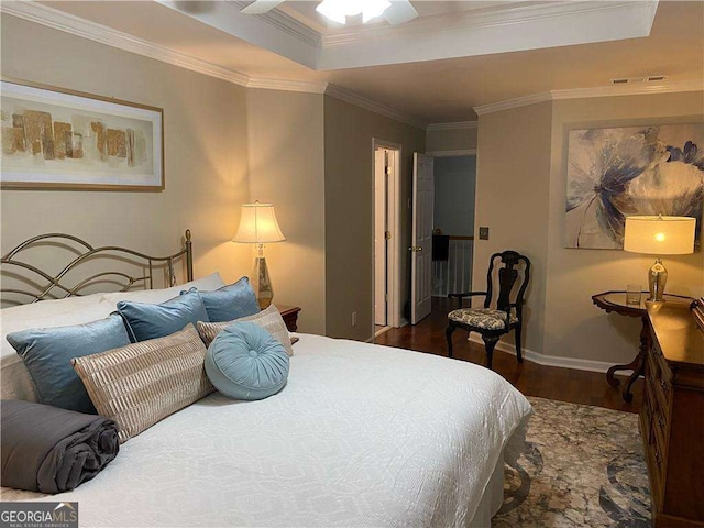 bedroom featuring a tray ceiling, visible vents, ornamental molding, wood finished floors, and baseboards