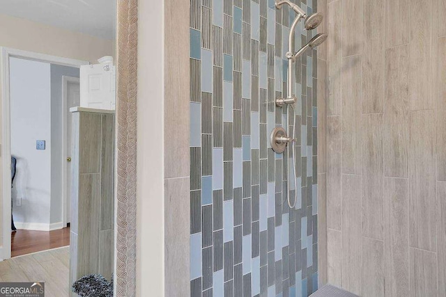 bathroom featuring tiled shower and wood finished floors