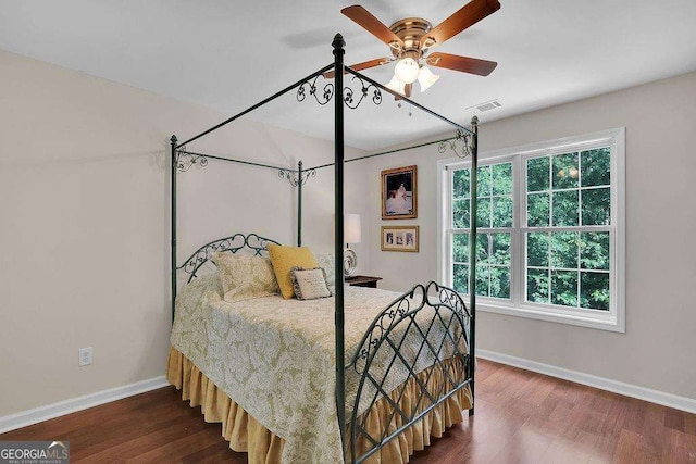 bedroom with dark wood-style floors, ceiling fan, visible vents, and baseboards