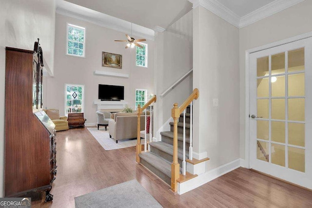 stairway featuring a healthy amount of sunlight, baseboards, ornamental molding, and wood finished floors