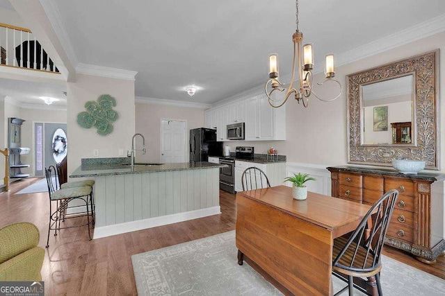 kitchen featuring wood finished floors, appliances with stainless steel finishes, a sink, and white cabinetry