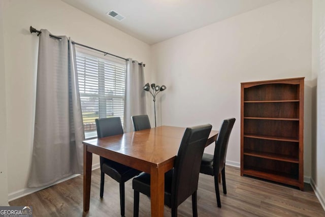 dining room featuring visible vents, baseboards, and wood finished floors