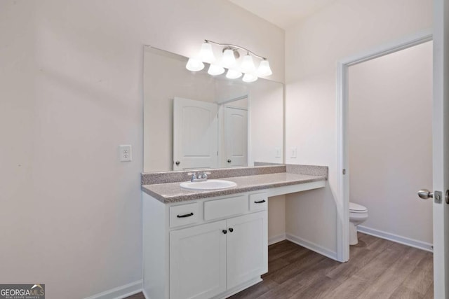 bathroom with toilet, baseboards, wood finished floors, and vanity