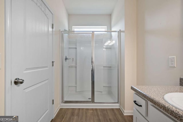 full bathroom featuring wood finished floors, a shower stall, and vanity