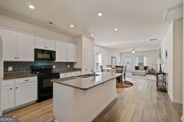 kitchen with black appliances, visible vents, white cabinets, and a sink