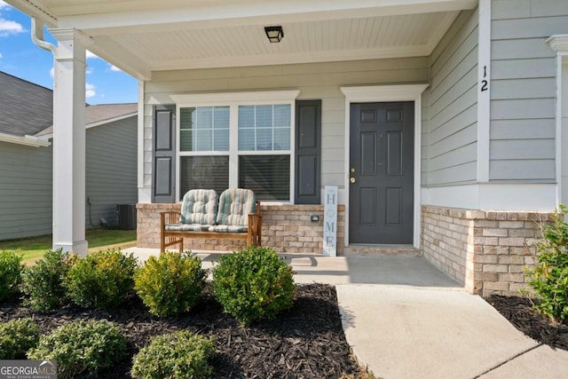 view of exterior entry with a porch and brick siding