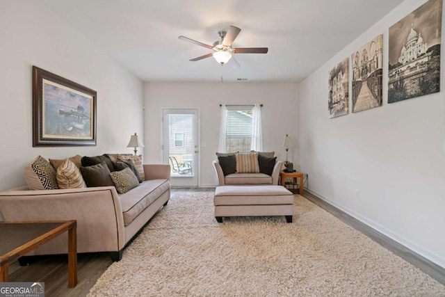 living room with a ceiling fan, baseboards, and wood finished floors