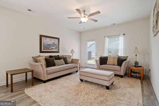 living area with a ceiling fan, visible vents, light wood-style flooring, and baseboards