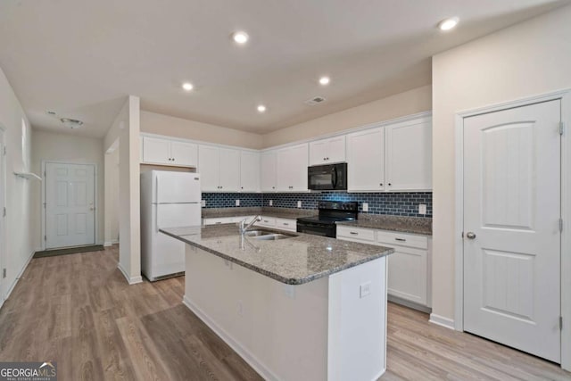 kitchen with a center island with sink, stone countertops, white cabinetry, a sink, and black appliances