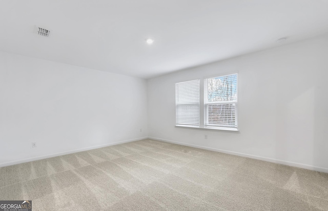 spare room with light colored carpet, visible vents, and baseboards