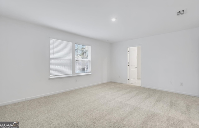 spare room with visible vents, light carpet, and baseboards