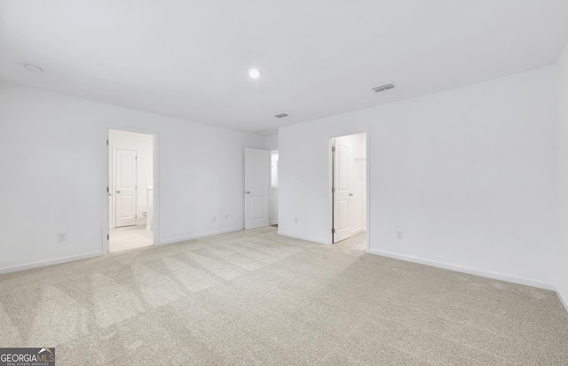 unfurnished bedroom featuring light carpet, connected bathroom, visible vents, and baseboards