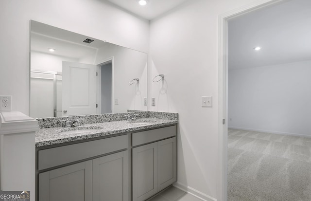 full bath featuring double vanity, baseboards, visible vents, and a sink