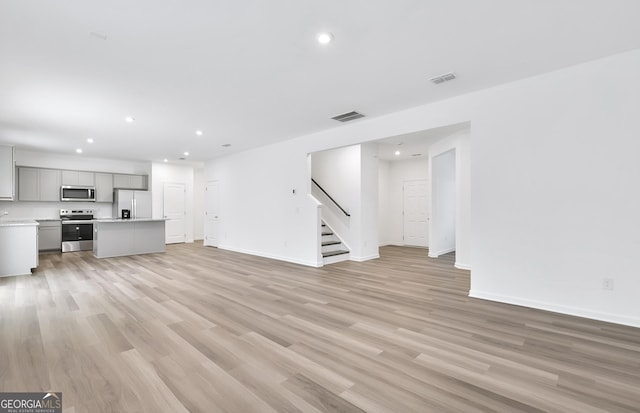 unfurnished living room with light wood-style flooring, stairs, visible vents, and recessed lighting