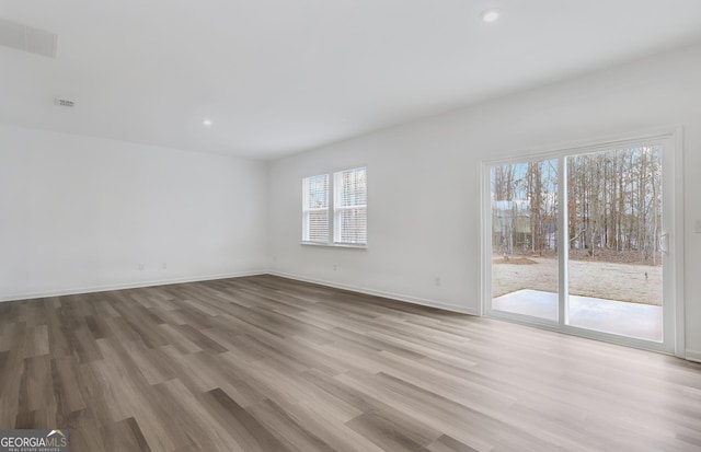 unfurnished living room featuring wood finished floors, visible vents, and baseboards