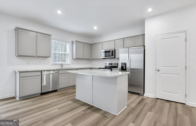 kitchen featuring appliances with stainless steel finishes, gray cabinets, a sink, and light wood-style flooring