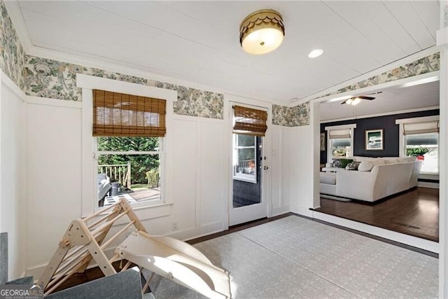 doorway featuring ornamental molding, a healthy amount of sunlight, wainscoting, and wallpapered walls