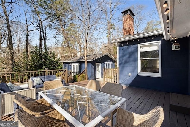 wooden terrace featuring an outdoor hangout area, an outdoor structure, and outdoor dining space