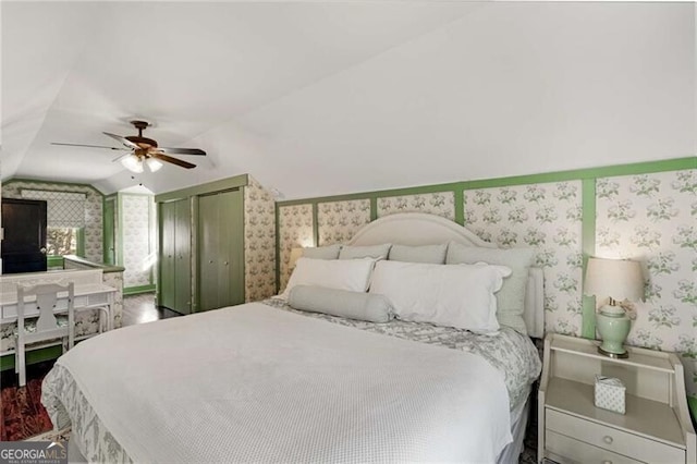 bedroom with lofted ceiling, a closet, ceiling fan, wood finished floors, and wallpapered walls