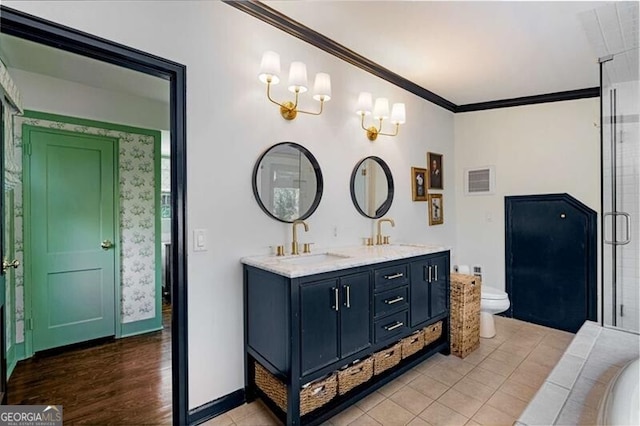 full bath with toilet, double vanity, ornamental molding, and a sink