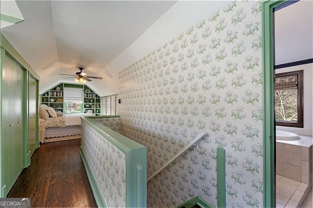 hall featuring lofted ceiling, wallpapered walls, built in features, and dark wood-style flooring