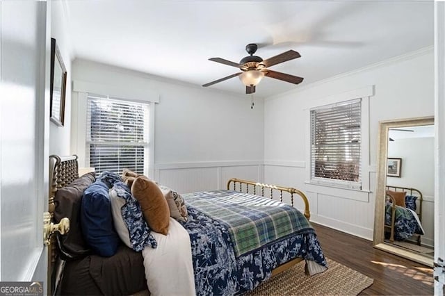 bedroom featuring crown molding, a ceiling fan, wood finished floors, and wainscoting